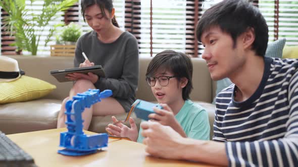 asian boy child with father mom control robot arm on Digital tablet and computer keyboard