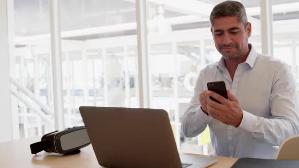 Businessman using mobile phone while working on laptop in modern offi 4k