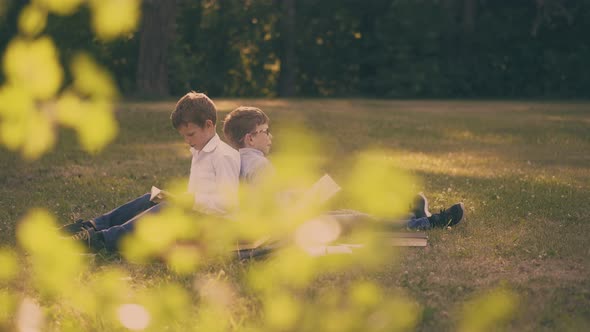 Children with Books and Schoolbags Do Home Task in Park