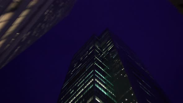 Tall skyscrapers viewed from directly below at night