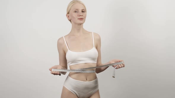Woman Ties a Measuring Tape Around Her Waist As a Symbol of Her Desire