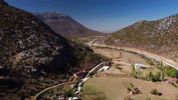 Scenery of Rocky Mountains and Asphalt Highway Lying Along Roadside Village