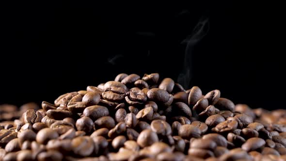 Smoke over a roasted coffee beans on the oven. Smooth motion of arabica coffee seeds.