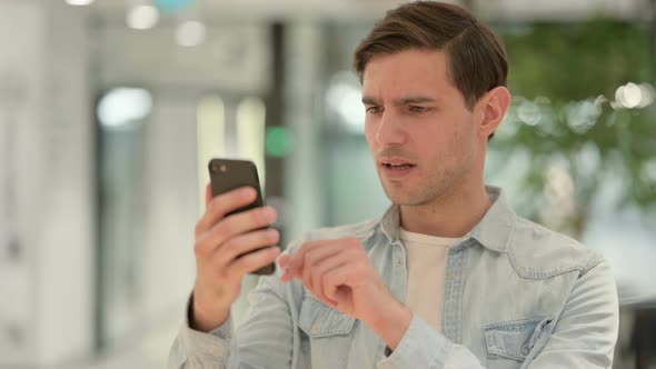 Portrait of Creative Young Man Loss on Smartphone