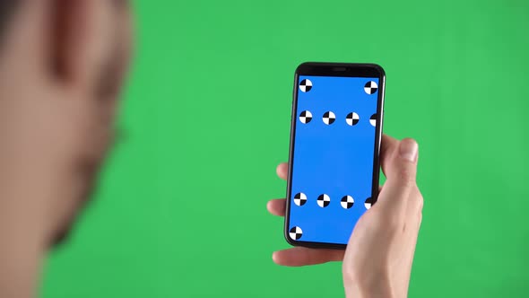 Man Holds Smartphone with Tracking Markers on the Display and Swiping Left Then Tap on Touch Screen