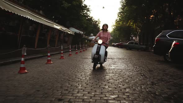 Young Beautiful Girl Riding Around City on Scooter at Sunrise