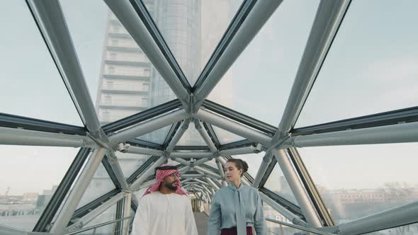 Diverse Business Couple Walking Along Glass Bridge