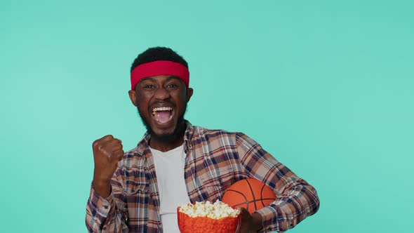 Bearded African American Young Man Basketball Fan Holding Ball Doing Winner Gesture Dancing Alone