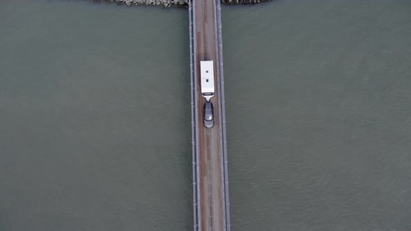Top View Of Vehicles Driving In The Bridge Over The Calm River. - aerial