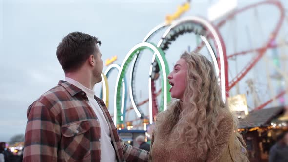 Happy couple having fun at amusement park and getting excited about a ride