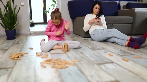 Indifferent Mother Use Mobile Phone Daughter Play Wooden Construction