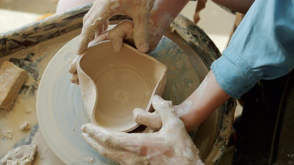 Top View of Male and Female Hands Making Heart Shape Bowl in Pottery Studio
