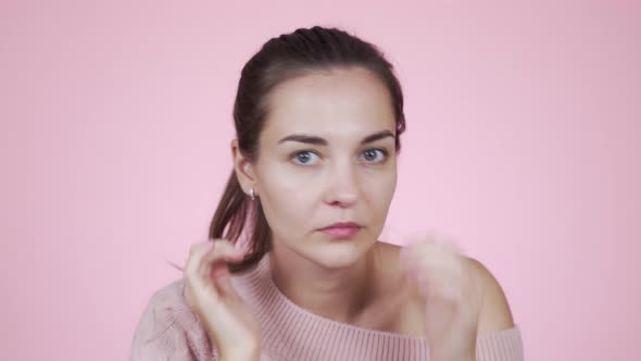Woman Looking at Camera Like Mirror Fixing Her Hair Isolated on Pink Background