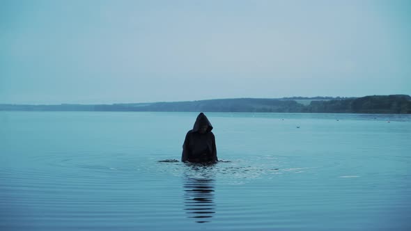 Terrible figure in a black robe in the water outdoor