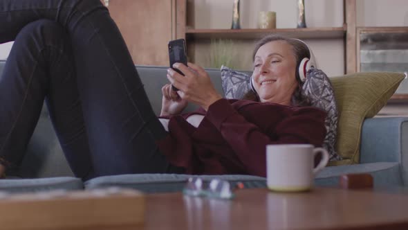 Woman wearing headphones using smartphone at home