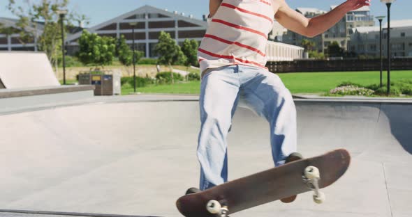 Caucasian man riding and jumping on skateboard on sunny day
