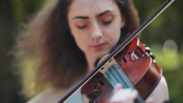 A Young Girl Plays the Violin in the City Park