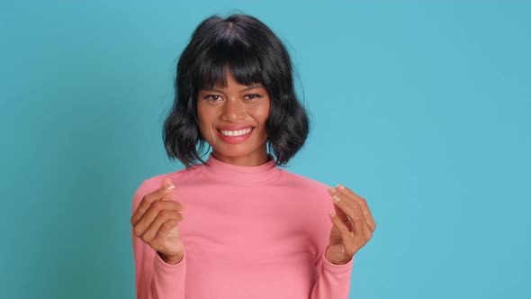 Young Woman Makes Money Gesture Has Idea of Big Profit Against Blue Background