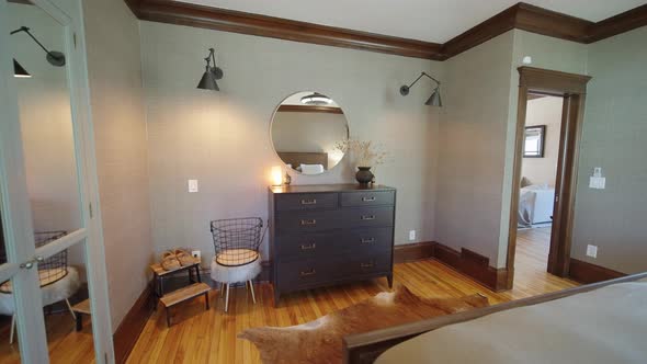 push in shot of a dresser in a modern bedroom with light fixtures, wood floors, mirror, and fur rug