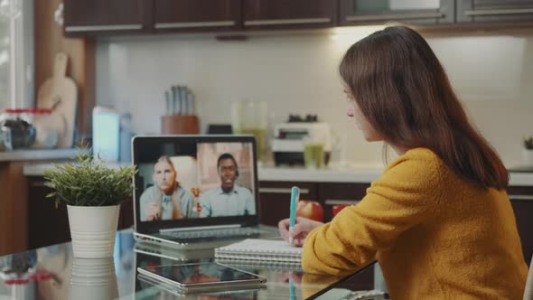 Young Woman Making Video Call with Two Multiracial Colleagues on Computer