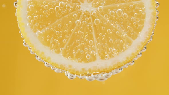 Lemon Slice in Carbonated Water on Yellow Background Fizzy Summer Drink Making Cocktail of Citrus