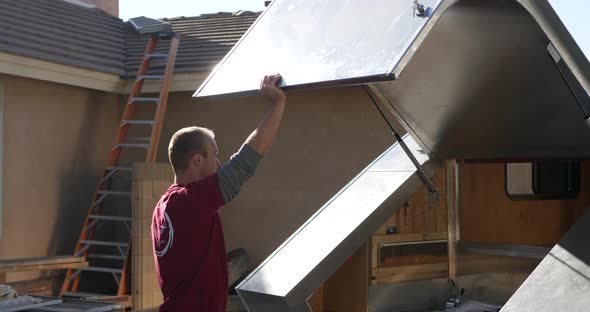 A custom travel trailer construction worker opening and raising the hatch back on the metal teardrop