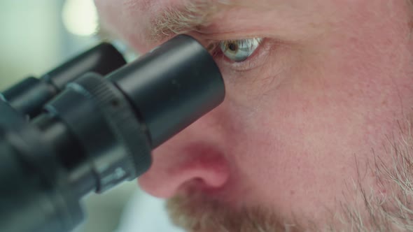 Experienced Scientist Looking through Microscope