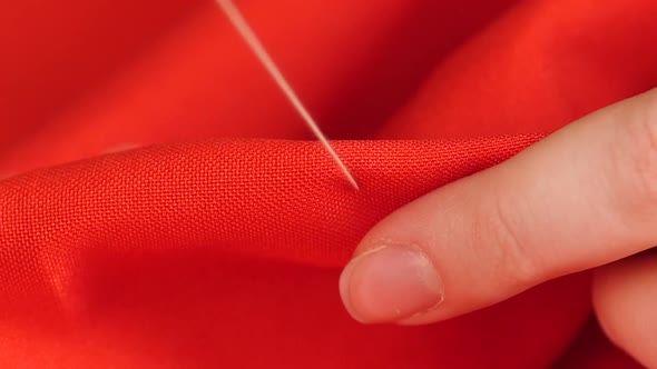 Woman Sewing with Needle, Thread and Thimble on Red Cloth, Close Up, Slow Motion