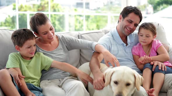 Cute Family Relaxing Together on the Couch with their Labrador Dog