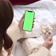 Woman holding modern smartphone with green screen chromakey in hand with cup of cocoa - VideoHive Item for Sale