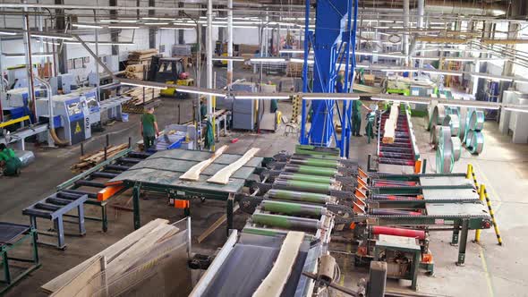 Woodworking factory indoors. Workers control the process of making boards