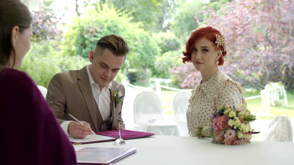 Newly Made Groom Sign Marriage Agreement Ceremony with Beautiful Redhaired Bride