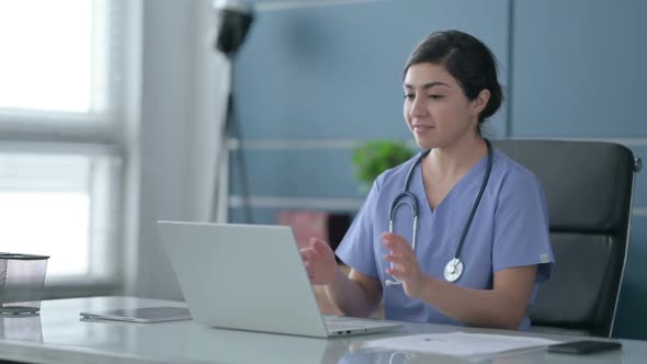 Indian Female Doctor Talking on Video Call on Laptop in Office