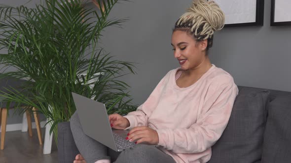 Young Happy Woman Using Laptop and Smiling on Couch at Home