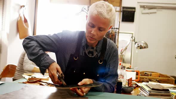 Craftswoman punching hole from leather punch machine