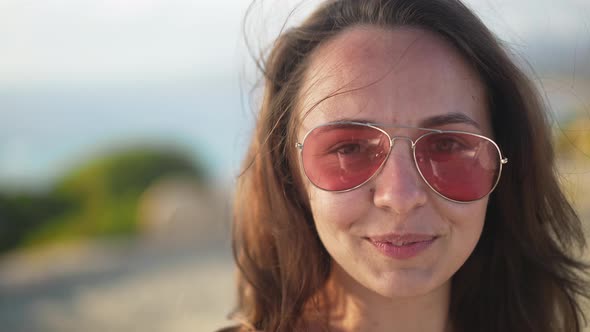 Headshot of Joyful Relaxed Caucasian Young Woman in Sunglasses Smiling Looking at Camera Standing at