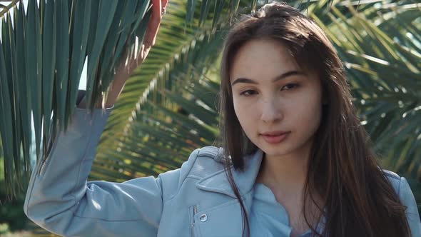 Young Brunette Girl Is Walking in a Tropical Garden in Daytime