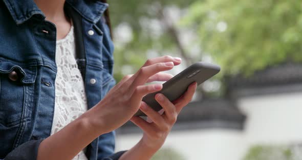 Woman use of mobile phone in Chinese garden