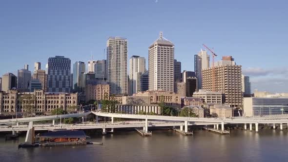 Aerial shot of motorway with cars passing base of tall city buildings along river Brisbane, Queensla