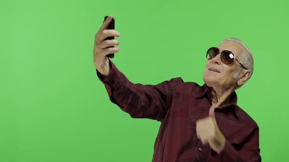 Senior Man Tourist in Sunglasses Make a Photo on a Smartphone. Selfie