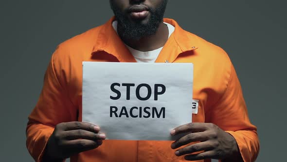 Stop Racism Phrase on Cardboard in Hands of Black Prisoner, Discrimination