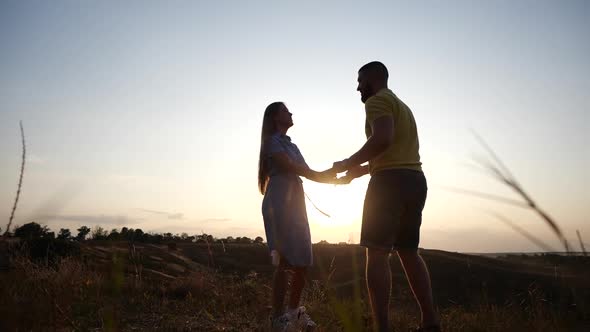 Happy Young Couple in Love Bearded Guy and Girl Hold Hands, Spinning on Grass in Deserted Field