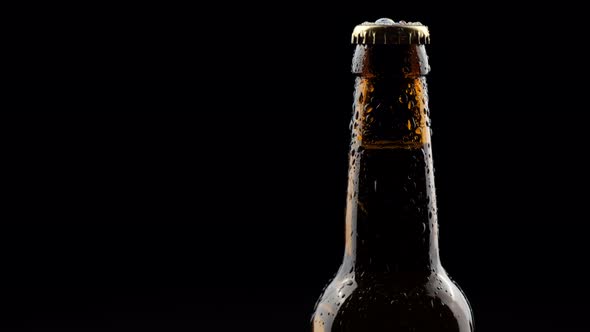 Glass Bottle of Beer Spinning in the Dark on a Black Background