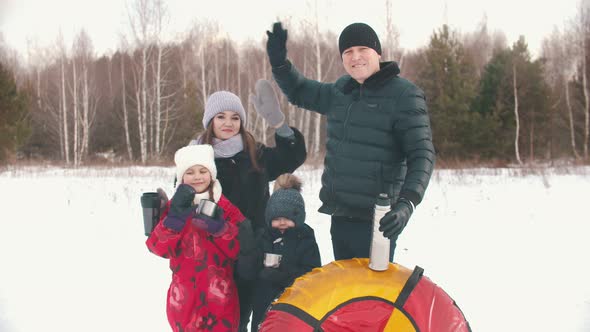 Family Standing Outdoors Holding Termos and Cups with Tea - Waving Hands