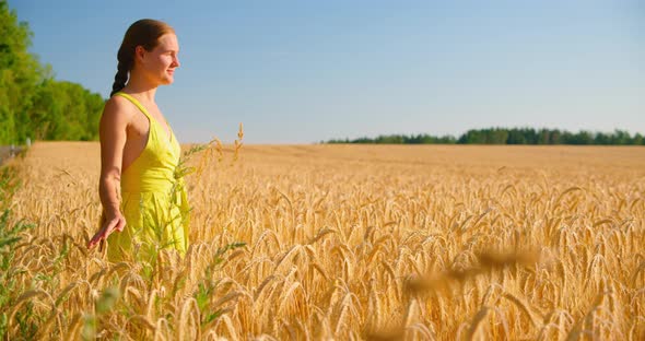 Happy Woman Walking in Summer Wheat Golden Field