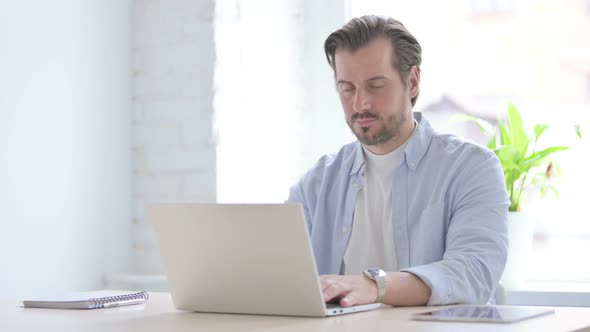 Young Man Showing Thumbs Down While Using Laptop