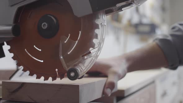 Hands of Carpenter Cutting off Thin Piece of Wood from Blank on Miter Saw