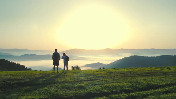 A Man and a Woman on Top of a Mountain Meet the Sunrise