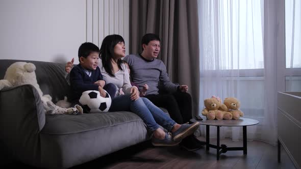 Excited Family of Soccer Fans Watching Match on TV