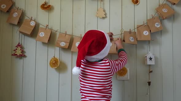 Boy in Pajamas Santa Cap Stretches for Paper Advent Calendar with Presents